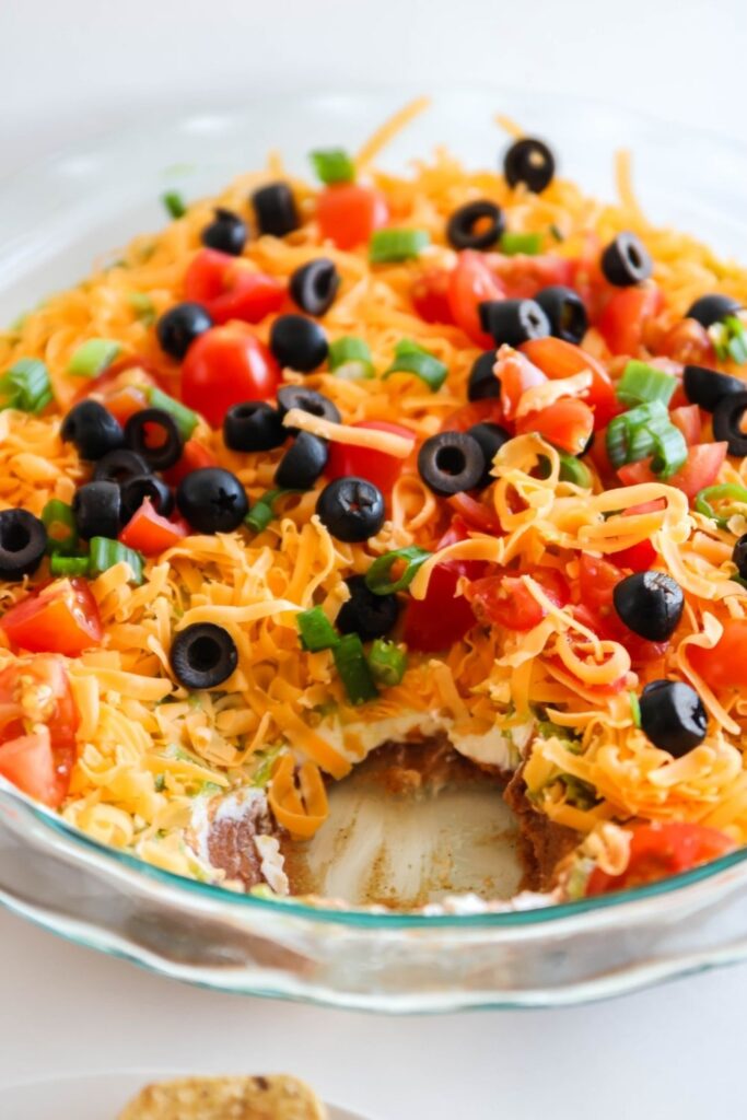 pan with 7 layer bean dip with scoop taken out of it