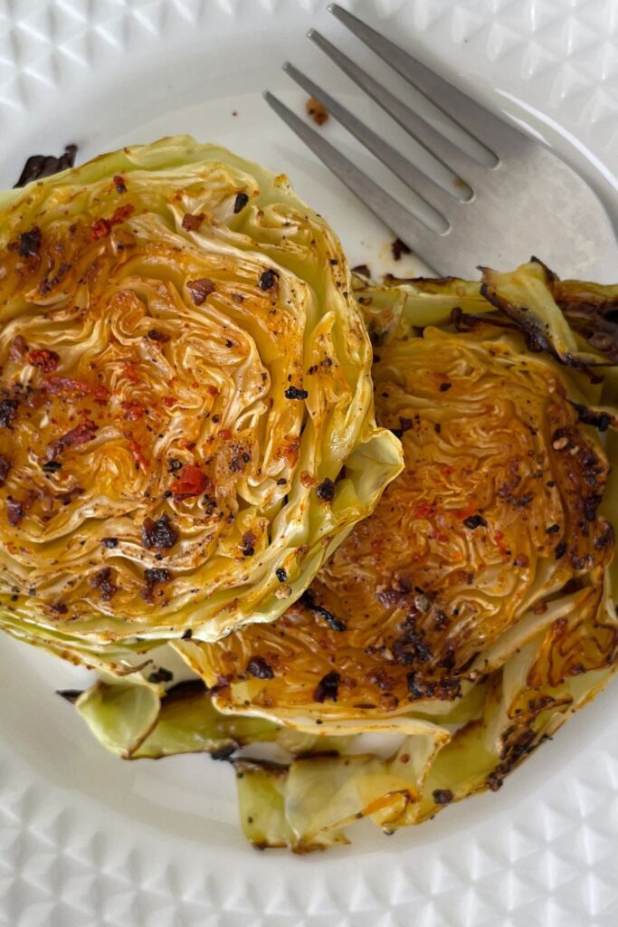 baked cabbage on a white plate with fork by it
