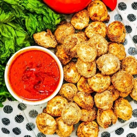fried tortellini on tray with sauce and veggies around it
