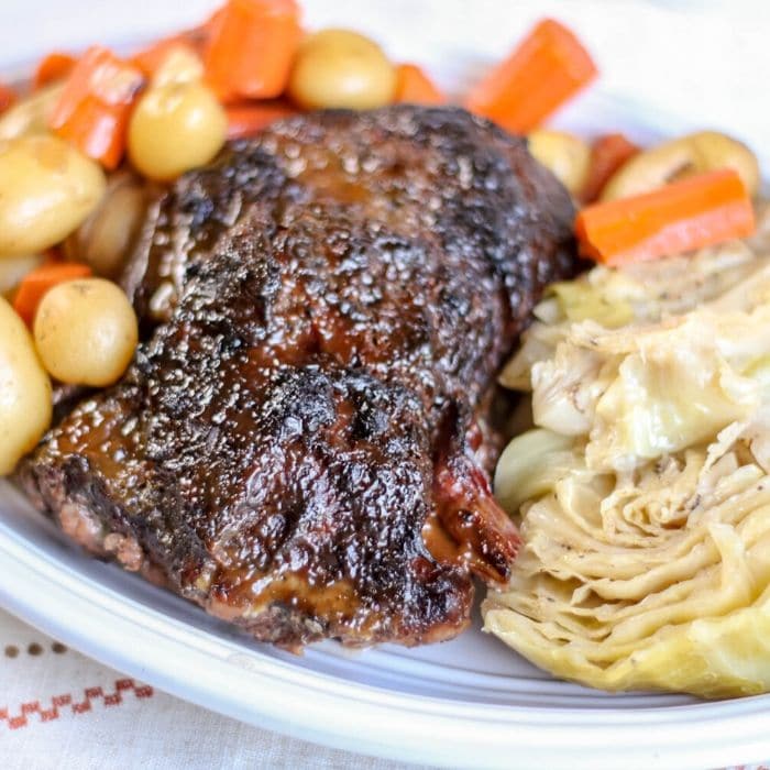 glazed corned beef, cabbage and vegetables sitting on a plate on table