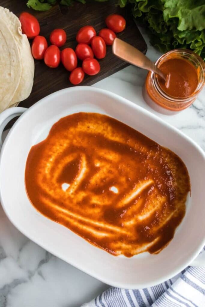 enchilada sauce in the bottom of a casserole pan