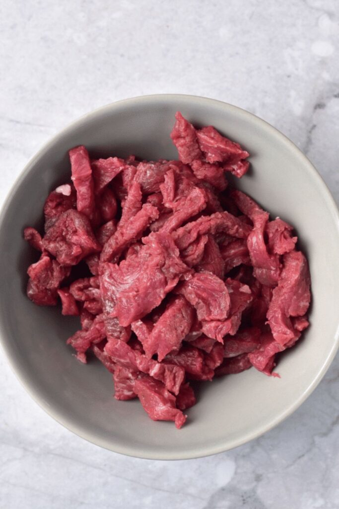 sliced steak in a grey bowl on table
