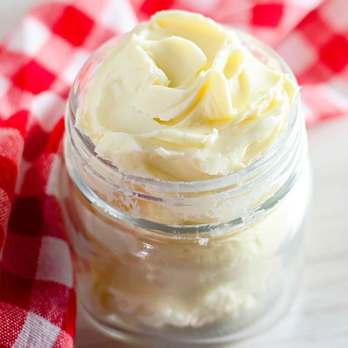 homemade butter in a small mason jar on table with red checkered towel behind jar