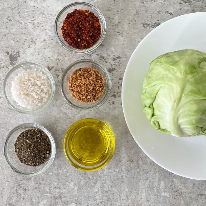 cabbage on a plate and spices in single bowls on a marble counter