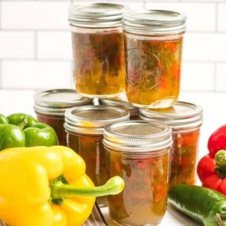 jars of pepper jelly with peppers around it