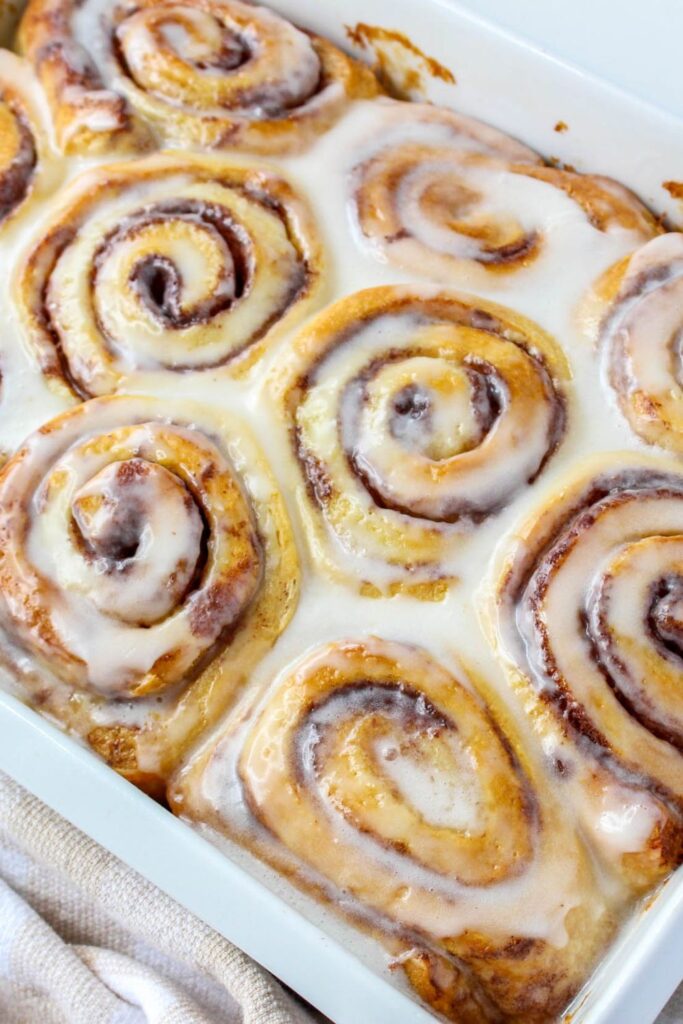 cinnamon rolls baked and frosting in a baking dish